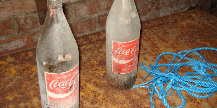 Two vintage Coca Cola bottles sit in an underground government office.