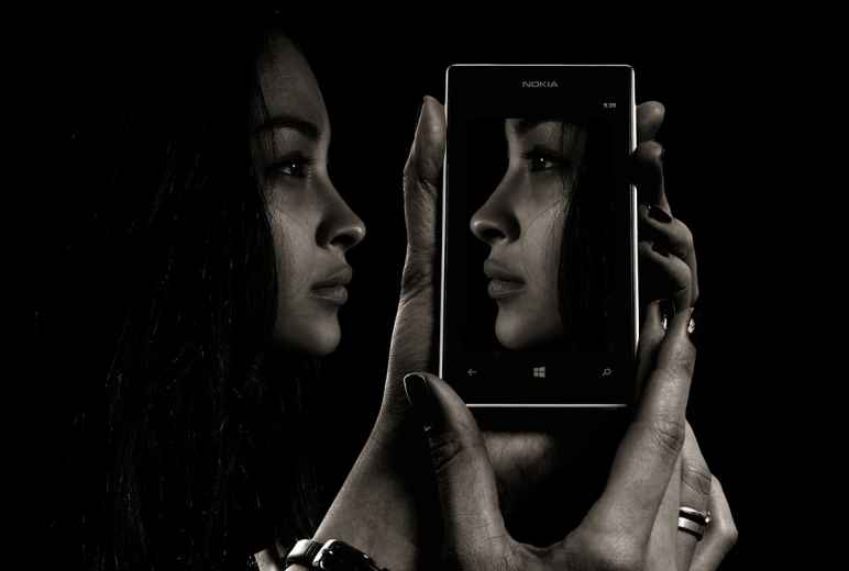 Woman Looking At Her Own Face On A Smart Phone