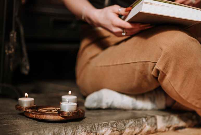 Woman Reading Old Book Near Burning Candles During Ritual